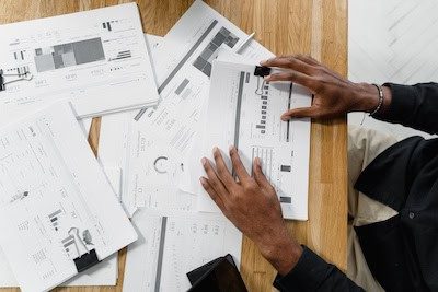 Hands reviewing printed financial plans on a wooden table for cash flow strategies