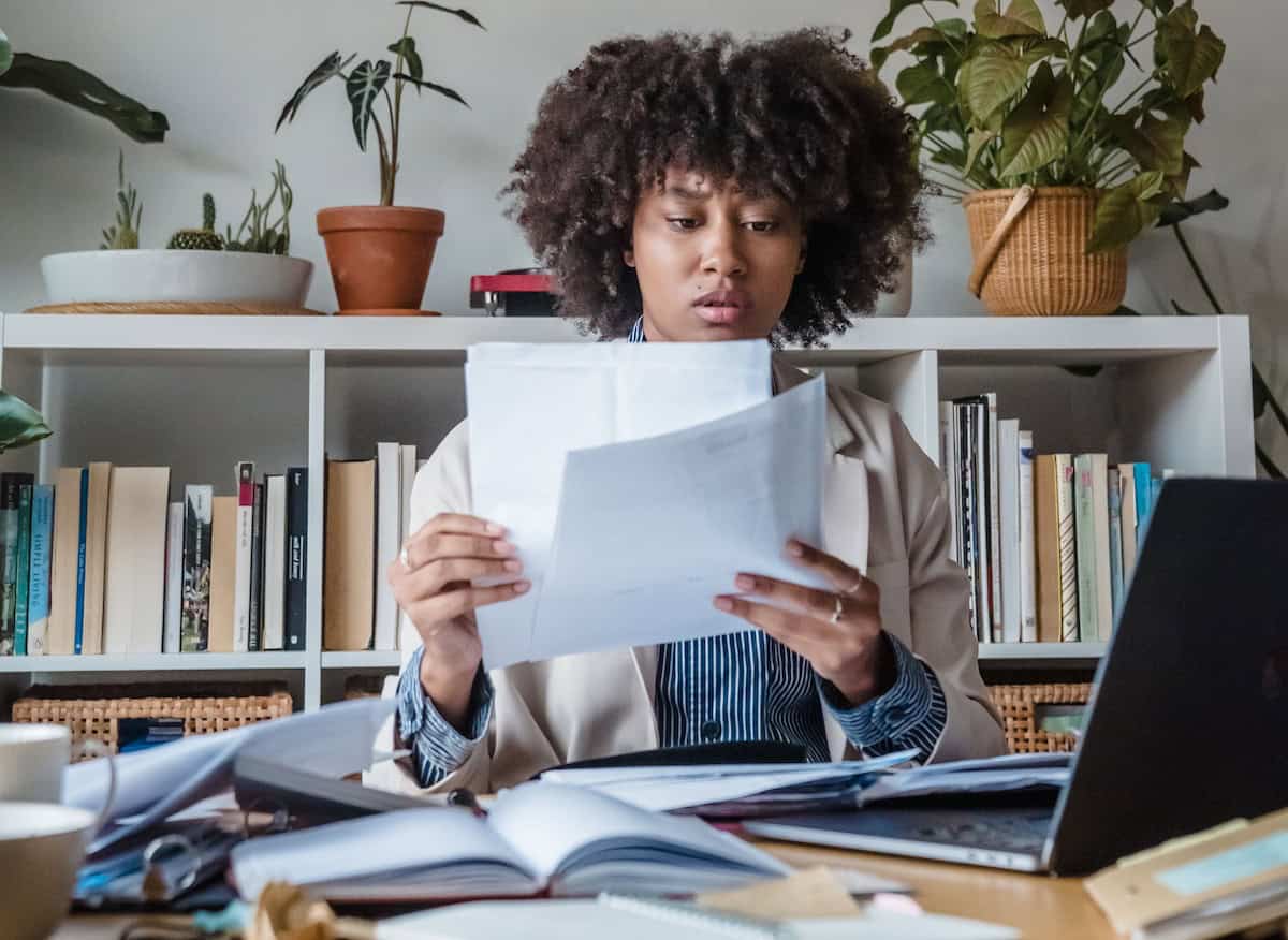 Small business owner reviewing cash flow documents at a desk with laptop