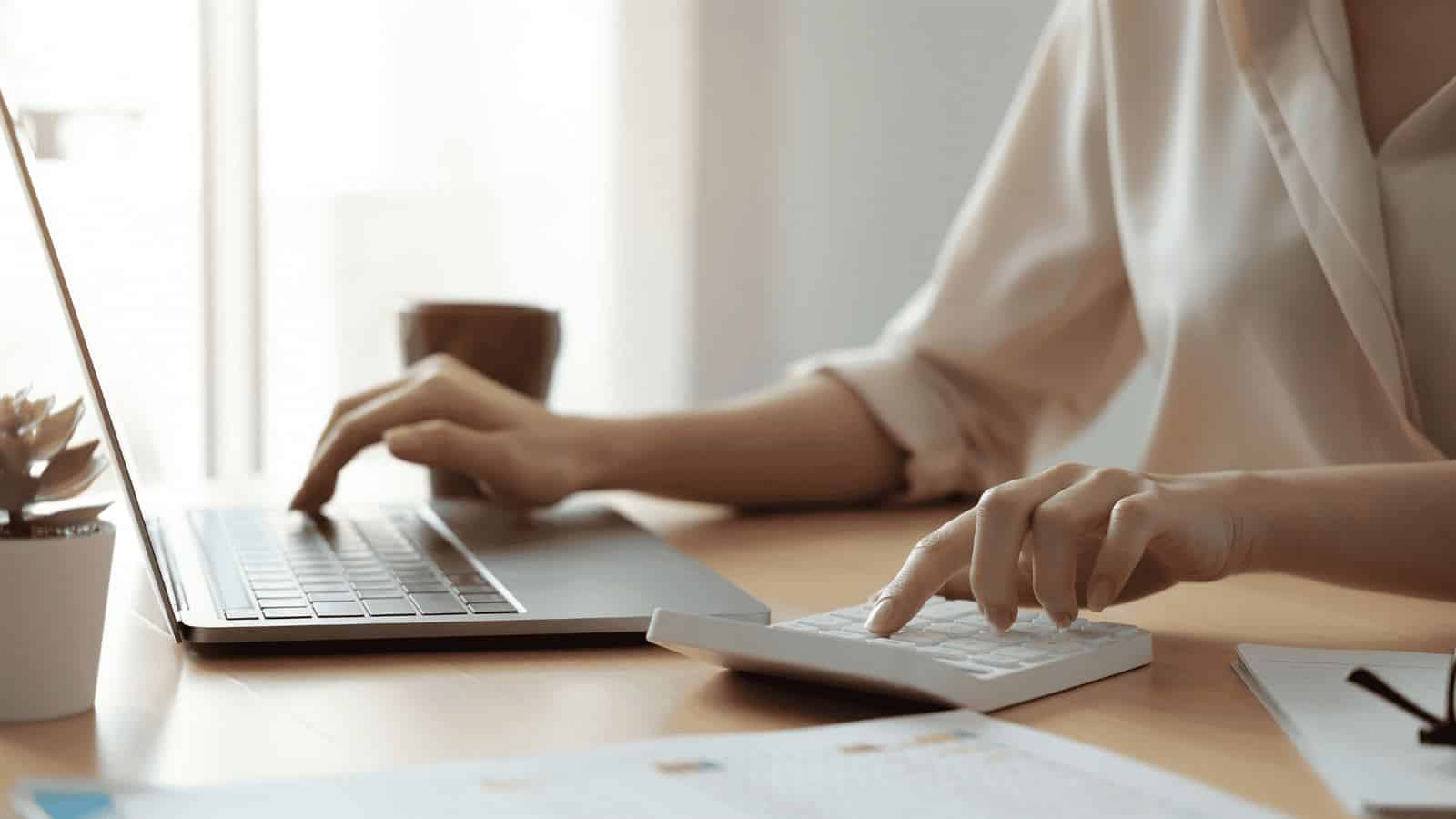 Woman using laptop and calculator to manage small business bookkeeping in Tulsa