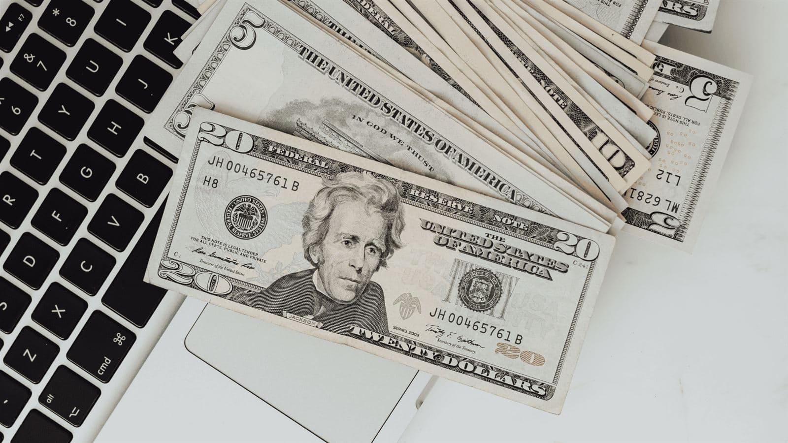 Cash bills spread across a laptop keyboard representing small business cash flow